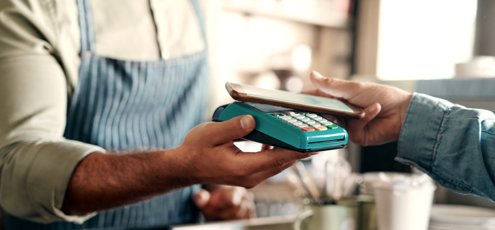 a person holding their smartphone up to a payment processor