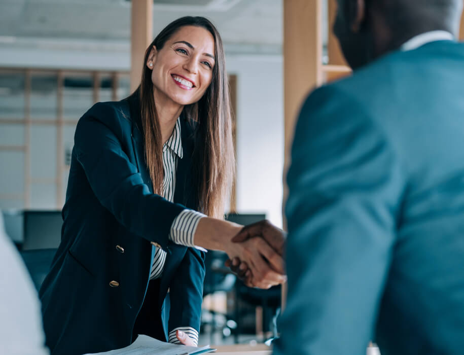 Business woman shaking the hand of a man who's slightly out of frame