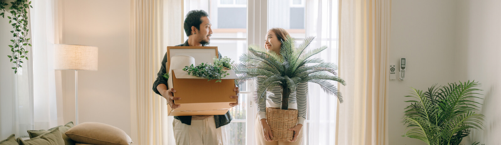 young couple moving boxes and house plants