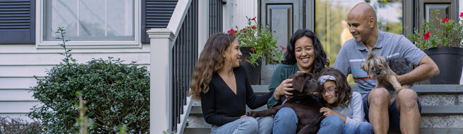 young family sitting outside on the front stairs of a house